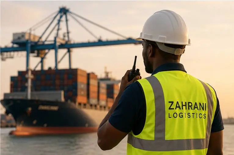 Agent portuaire Zahrani Logistics en gilet haute visibilité supervisant un porte-conteneurs à quai