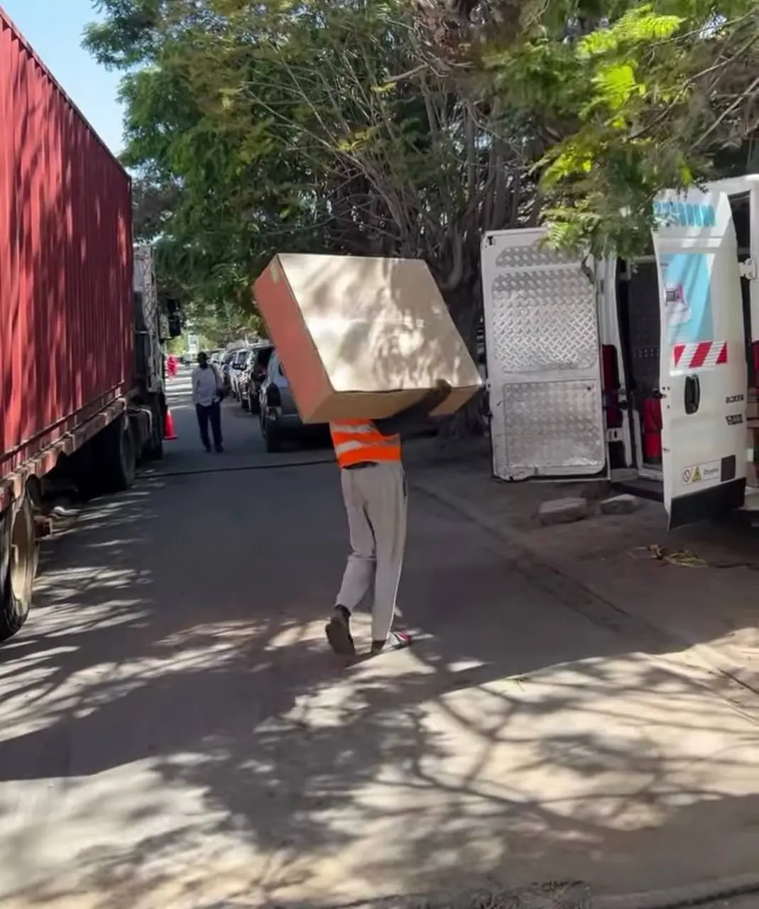 Agent Zahrani Logistics transportant un colis volumineux entre deux camions